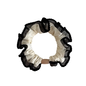 Beige scrunchie with black lace edging and wood cylinder detail for ponytail styling