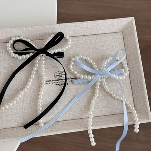 Détail d'une barrette en perles élégante avec de longs rubans en soie noir et bleu clair