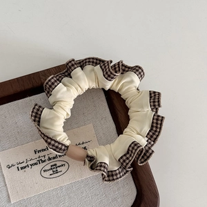 Detail view of coffee plaid scrunchie with layered ruffles and a central button