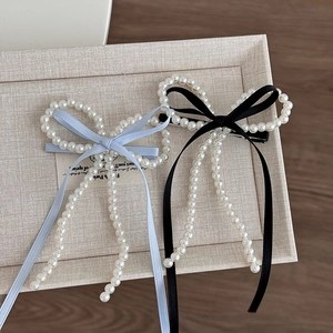 Vue détaillée de barrettes à cheveux en perles avec rubans en soie bleus et noirs