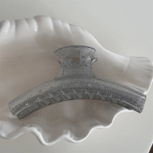 Detail view of large silver glitter hair claw clip with smooth arc shape and metal spring