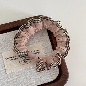 Detailed view of apricot scrunchie with vintage brown plaid lace trim on fabric
