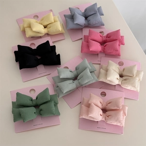 Vue à plat de lots de barrettes à nœuds en tissu coloré en jaune, bleu, noir et pastel