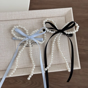 Détail des barrettes nœuds en perles avec des rubans de soie bleus et noirs élégants