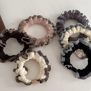 Detail view of plaid lace scrunchies in brown, pink, beige, and black fabric textures