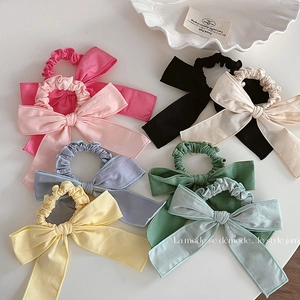 Vue à plat de chouchous colorés en tissu avec nœuds en rose, jaune et vert sur blanc