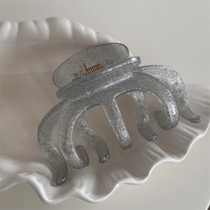 Close-up of glitter silver octopus hair claw clip on white ceramic shell tray