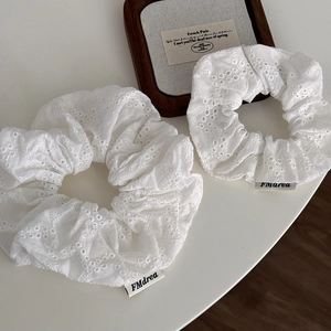 Set of two elegant cream scrunchies with intricate hollow flower embroidery and chic brand label