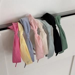 Détail d'un lot de 8 bandeaux avec nœud en tissu coloré suspendus au tiroir