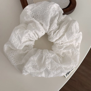 Detail of floral hollow embroidery on white cotton scrunchie with scalloped edge