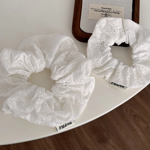 Detail showing white hollow embroidery flower scrunchies with fine cotton texture