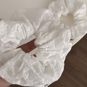 Close-up of white scrunchies featuring delicate eyelet lace and floral embroidery details