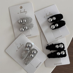 Close-up of sparkling sequin hair clips with silver beads on a display card for styling