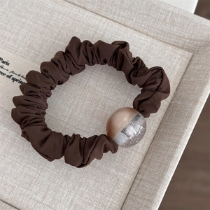 Close-up of a dark coffee brown scrunchie with a shimmering bicolor decorative bead