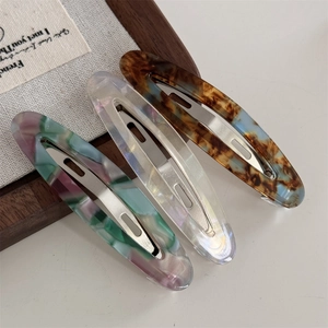 Trois barrettes en acétate aux motifs écaille, perle blanche et marbre coloré