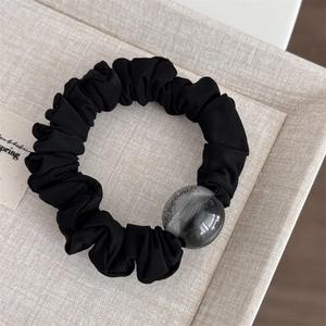 Detail of black scrunchie with a shimmering gradient resin bead decoration