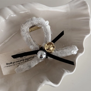 Close-up of sequin lace hair claw with silver beads and black bowknot details