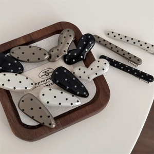 Retro polka dot hair clip set in heart and teardrop shapes on a wooden display tray