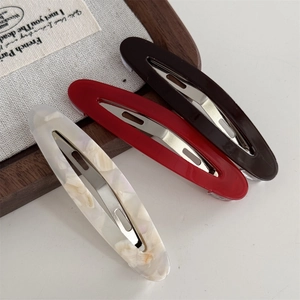 Détail de trois barrettes en acétate de couleur blanc crème, rouge foncé et noir café