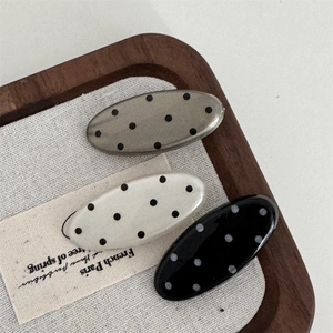 Detailed view of three French retro polka dot hair clips on a soft canvas surface