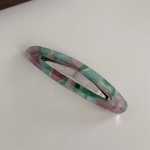 Détail d'une longue barrette ovale en acétate avec texture marbrée colorée et fermoir en métal