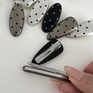 Close-up of polka dot hair clips in black and white with silver metal duckbill clips