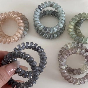 Cinq élastiques spirales motif marbré en couleurs pastel sur fond blanc épuré