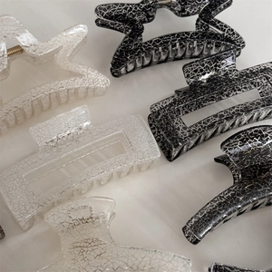 Detail view of square and star-shaped hair claws with black and white marble pattern texture