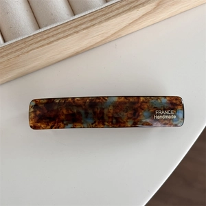 Detailed macro view of acetate hair clip with gold lettering and tortoise shell texture