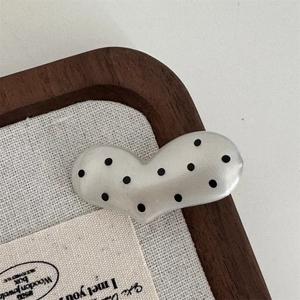 Close-up of heart hair clip with retro black polka dots and cream pearl finish