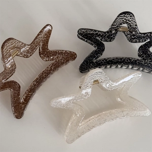 Close-up of star-shaped hair claws with marble texture in black, brown and beige colors