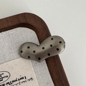 Macro detail of retro heart hair clip with black polka dots on antique silver finish