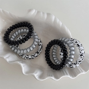 Cow print and metallic spiral hair ties set in a minimalist ceramic shell tray