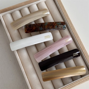 Detail view of 6-piece acetate hair clip set in varied colors on a beige tray