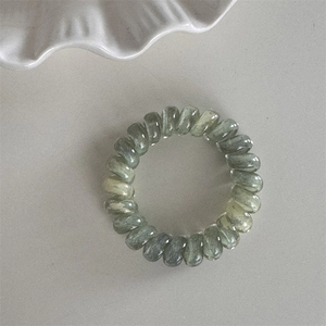 Détail d'élastique spirale vert mousse avec texture marbrée translucide et design souple