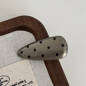 Detailed view of a vintage polka dot hair clip on a textured linen background