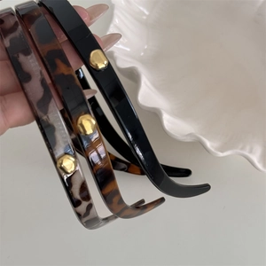 Close-up of leopard print and solid hairbands featuring a unique gold metal buckle detail