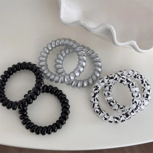 Detail showing set of six elastic spiral hair ties with milk cow pattern and satin gray finish