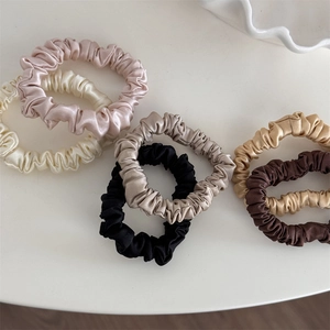 Silk satin hair scrunchies set in neutral colors arranged on a white minimalist background