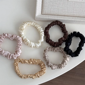 Detailed close-up of six premium silk satin hair scrunchies in various elegant colors