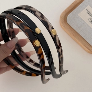 Elegant leopard print and black headbands with gold metallic studs on wood tray