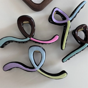 Close-up of wavy resin hair claws with macaron colors and glossy finish on a white background