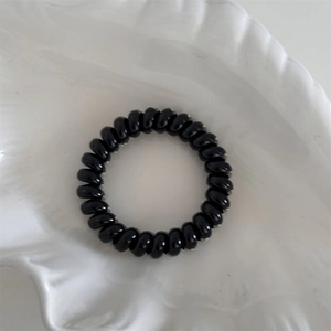 Close-up of black spiral hair tie with high elasticity in a decorative shell tray