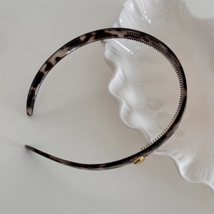 Detailed view of leopard pattern headband with gold bead accent and non-slip inner teeth