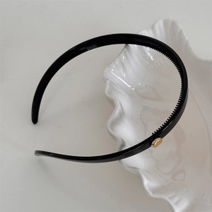 Detail view of black non-slip headband with gold bead accent on white textured dish