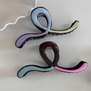 Detail view of wavy resin claw clips featuring a vibrant multi-color拼接 design and metal spring