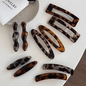 Elegant tortoise shell acrylic hair clips set in oval and rectangle shapes on white tray
