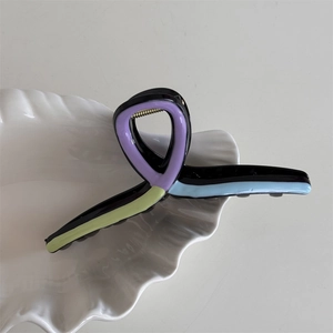 Macro shot of wavy hair claw clip with colorful oil drip pattern in blue and purple