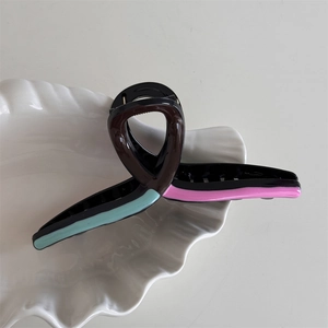 Close-up of color-block wavy hair claw clip on a decorative white shell tray