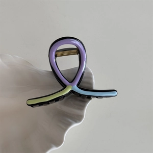 Detail view of wave-shaped hair claw clip with colorful oil-dripped finish on shell tray